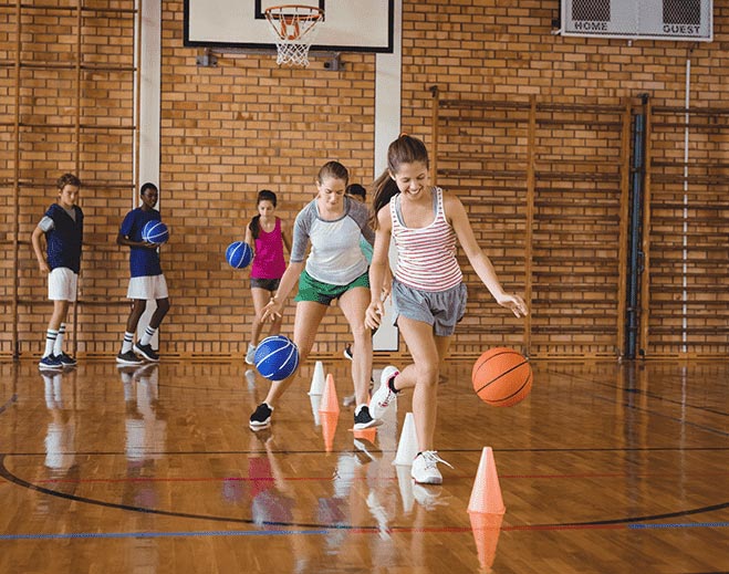 Children practicing basketball drills indoors