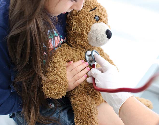 Child holding teddy bear during exam