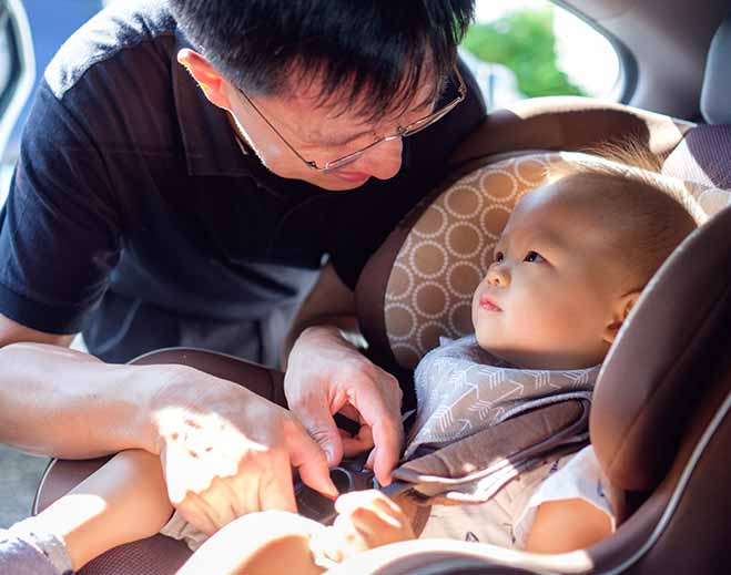 Caregiver securing child in car seat