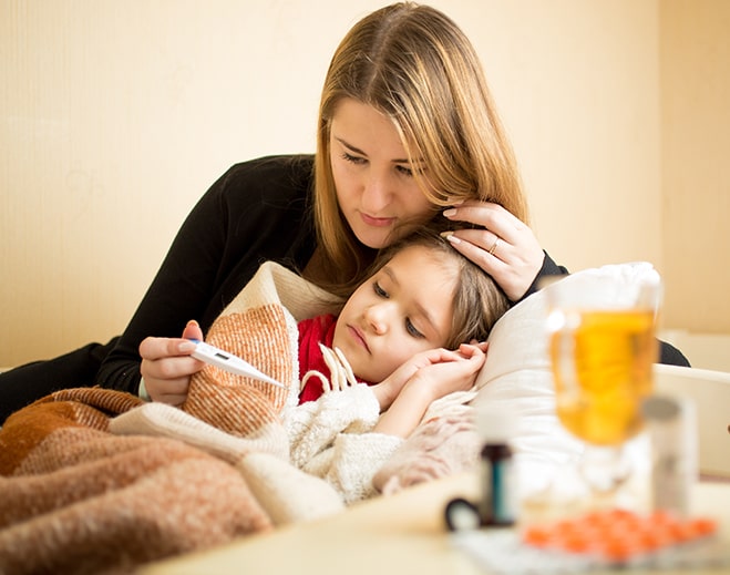 Caregiver checking child's temperature at home