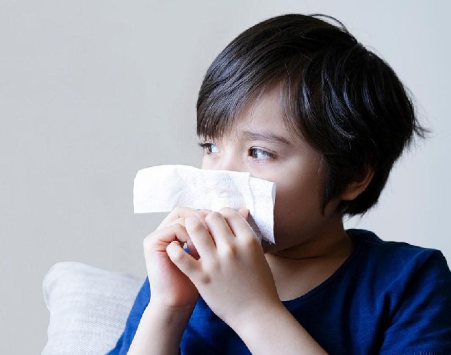 Child holding tissue to nose